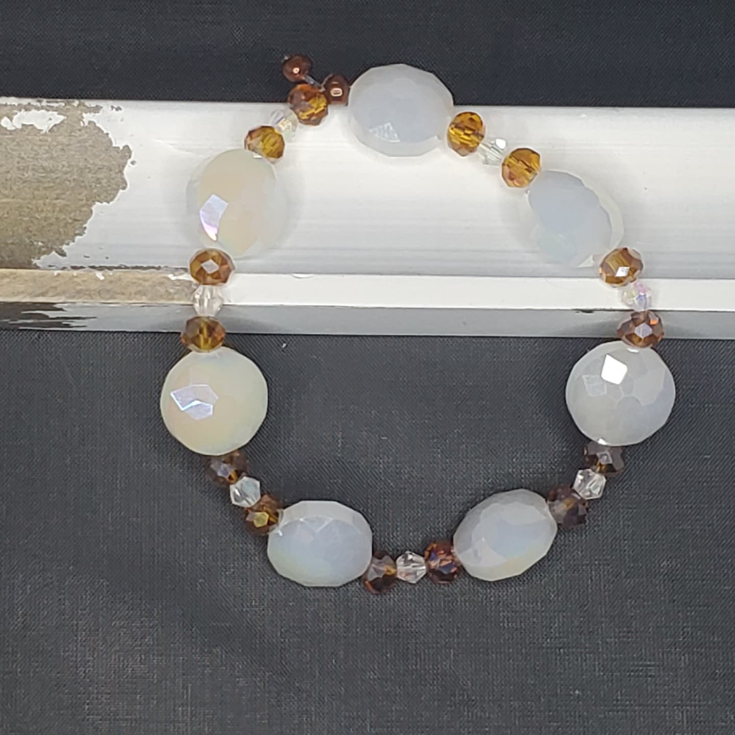 a bracelet of alternating small gold gem beads and large white gem beads