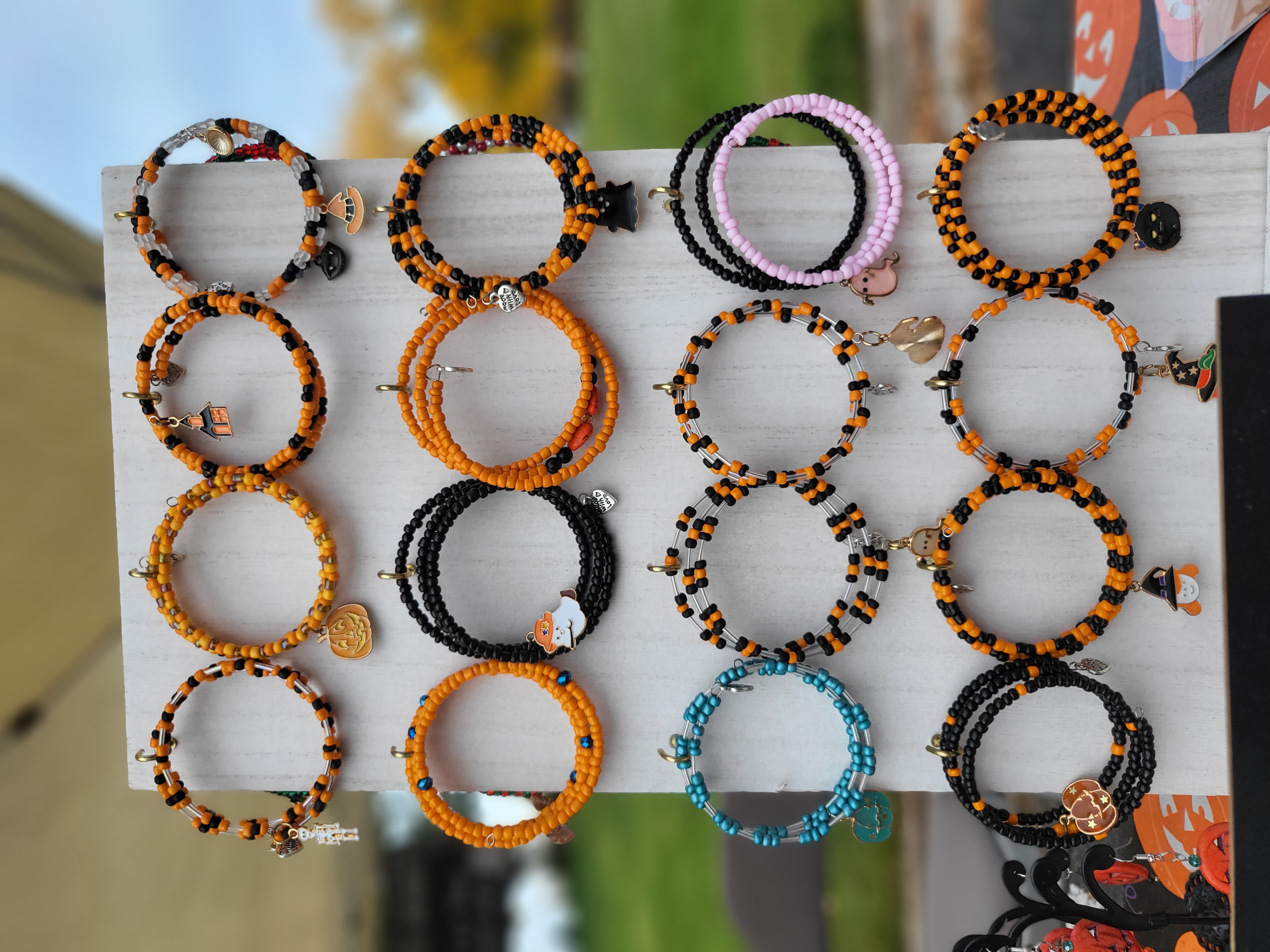 a display of halloween-themed bracelets, they are orange and black and have various halloween pendants on them